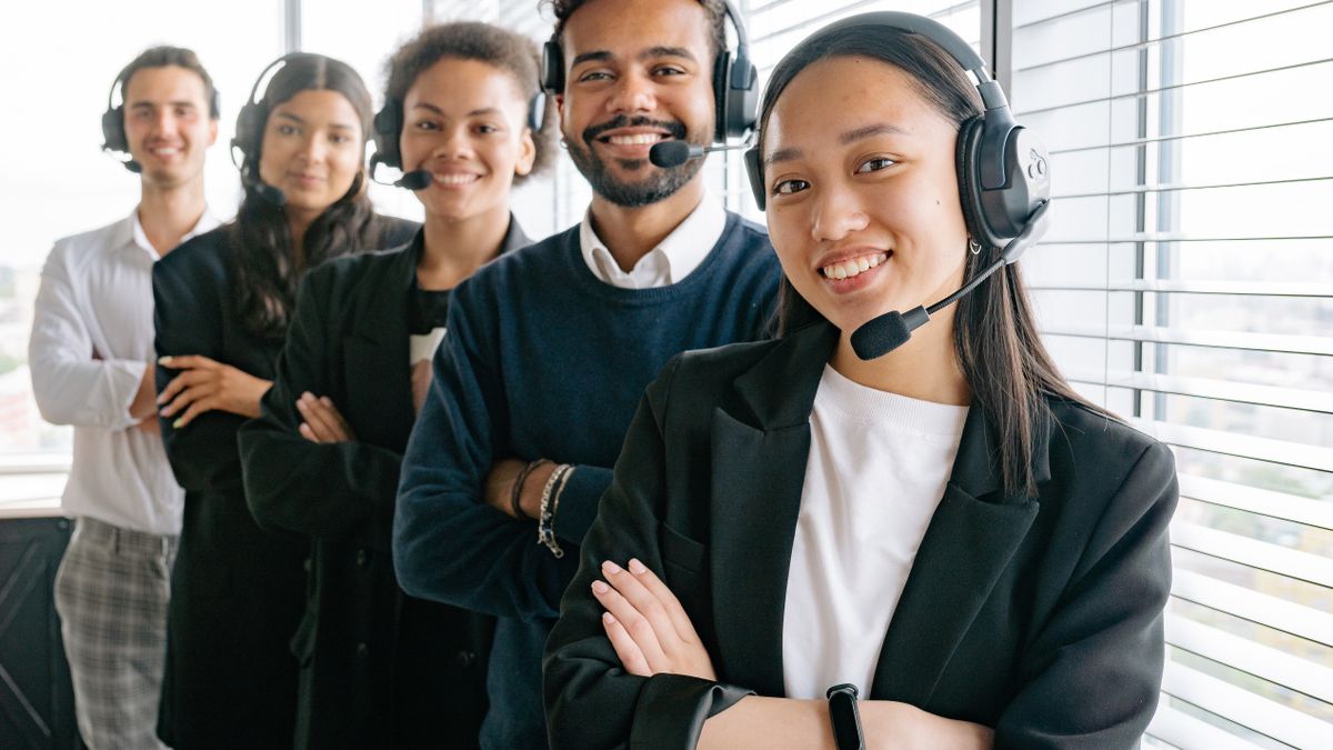 Equipo de atención al cliente con auriculares trabajando frente a ordenadores en una oficina diáfana